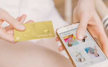 Smartphone mit Ansicht auf einen Online Shop. Danaben wir die TF Mastercard Gold gehalten.